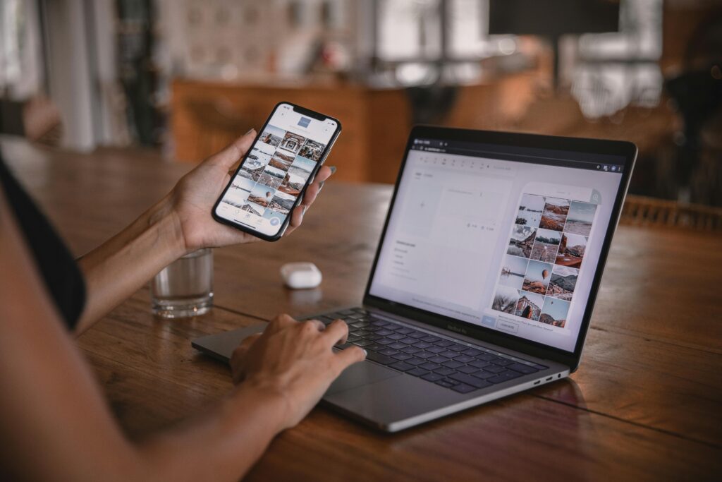 Woman using smartphone and laptop to create interactive content for web design firms’ social platforms