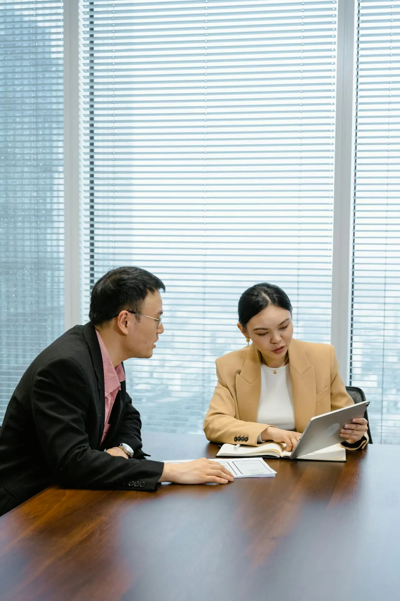 Two website design and development professionals sit at a table in a modern office, engaged in discussion.  