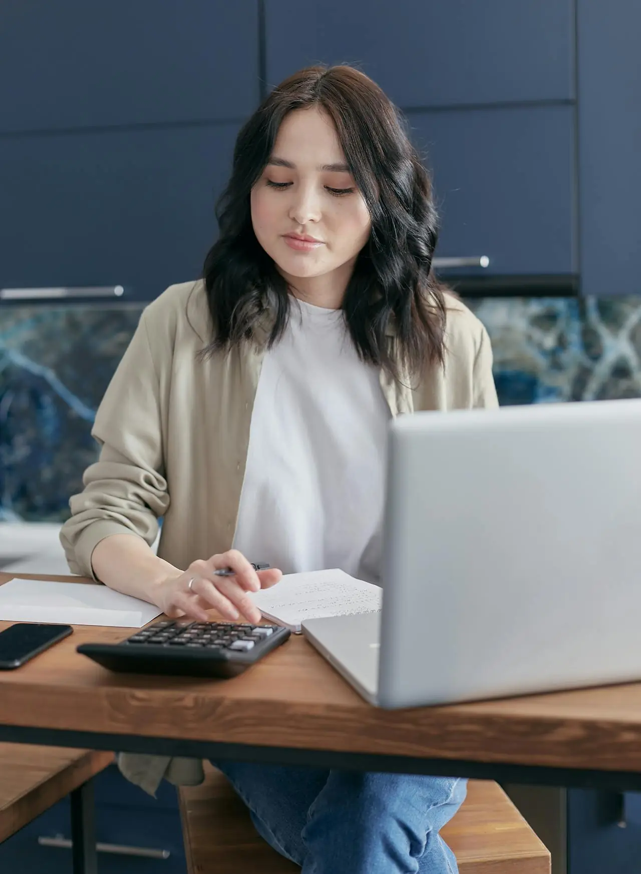 Woman in an office uses a calculator, calculating a digital marketing budget. 