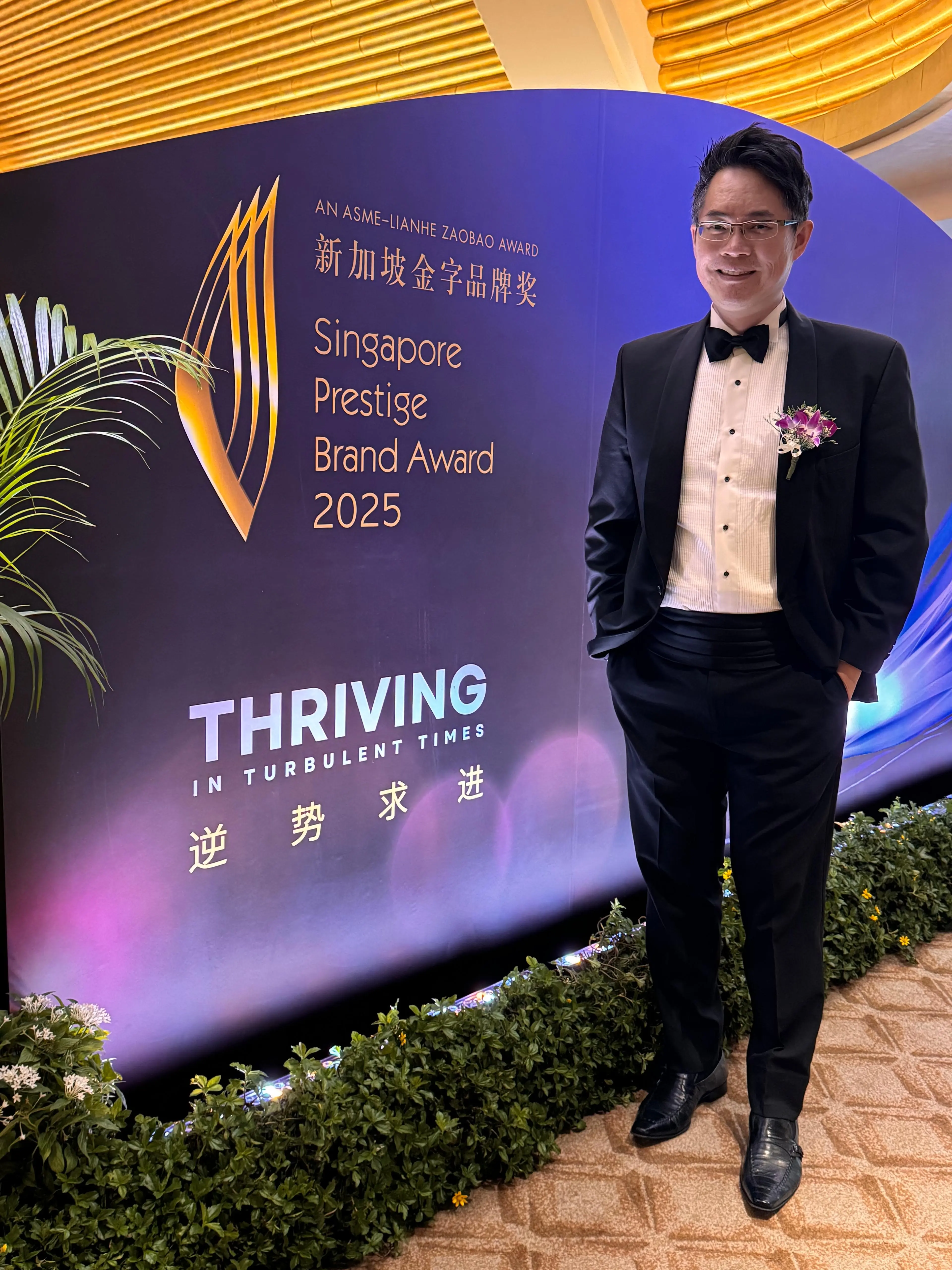 Bobby Tan, Director of BlueCube Media, standing in front of a screen displaying the SPBA 2025 logo and tagline.