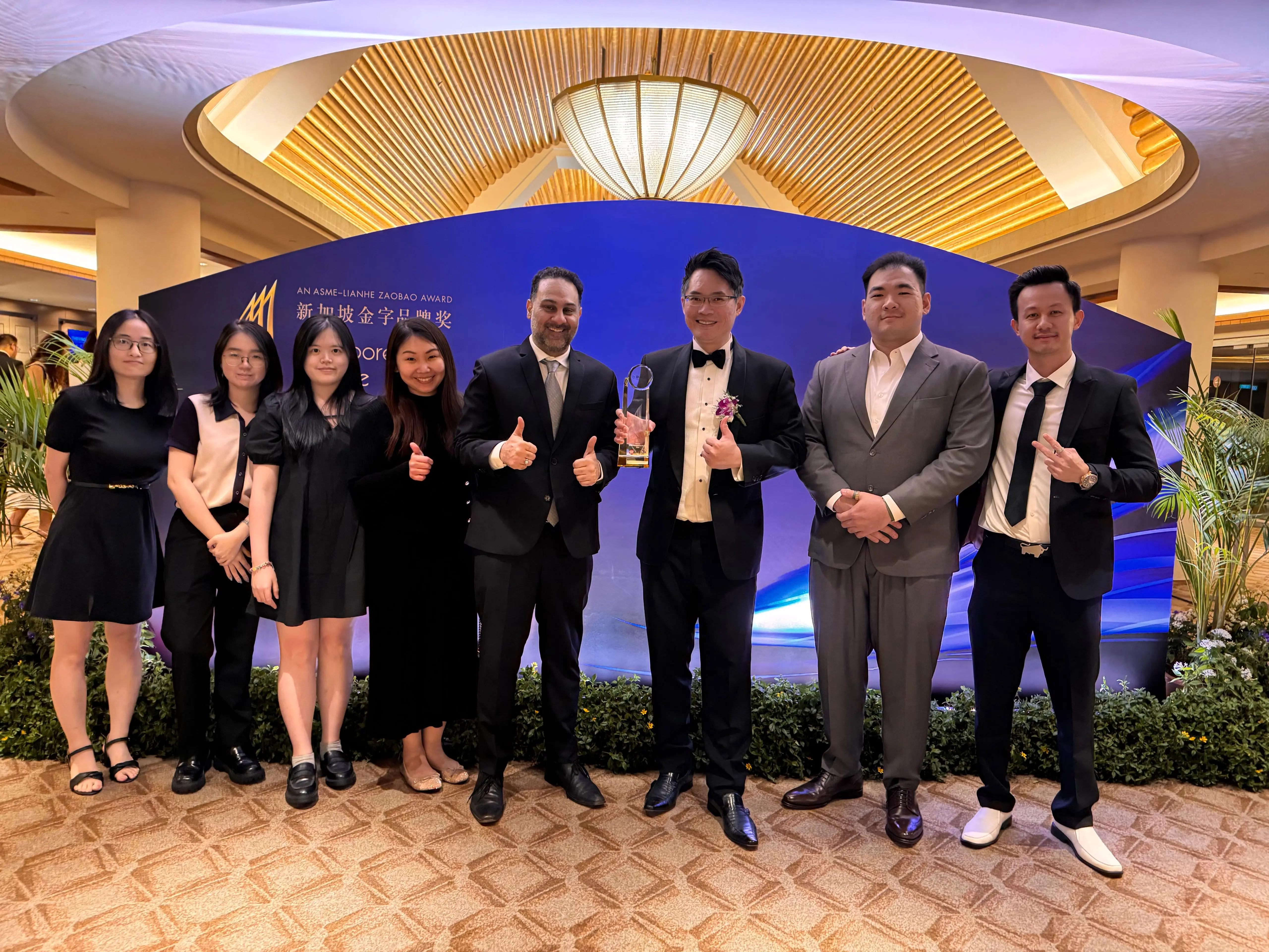 The BlueCube Media team gathered in front of a screen, holding the award trophy.