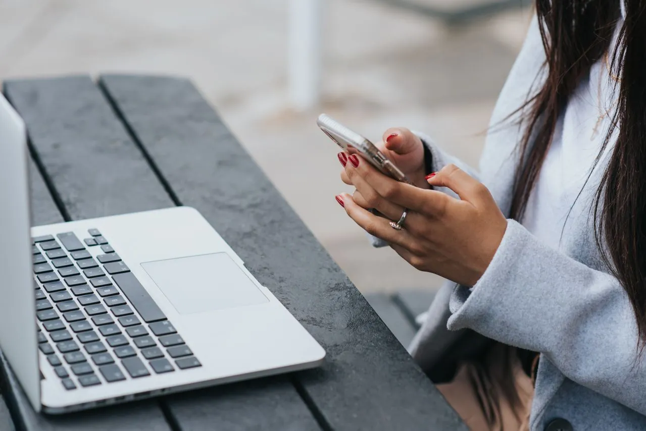 Business professional using a smartphone and laptop to access a mobile-friendly website developed by a web development company.